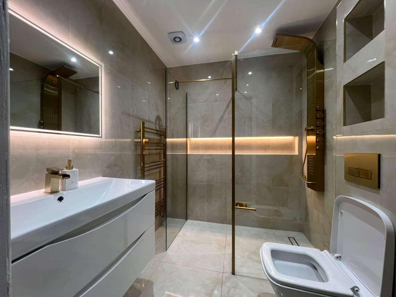 After — bathroom fitted by Lynx in Romford with marble-effect tiling, walk-in shower and brass fittings