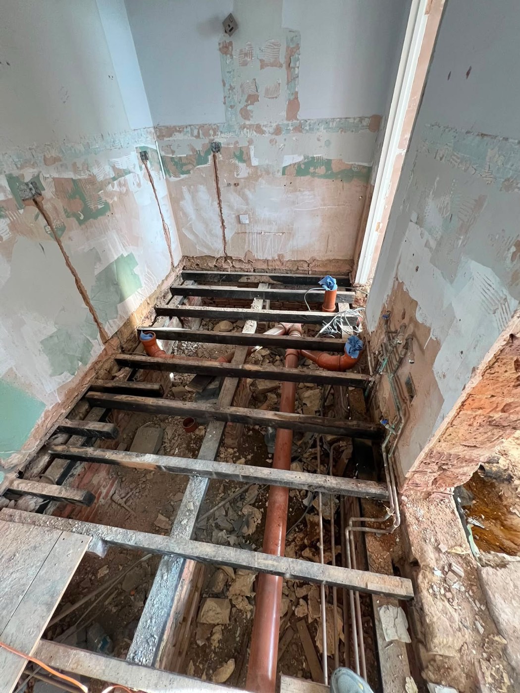 Before — the Romford bathroom stripped back to joists and brickwork before refitting
